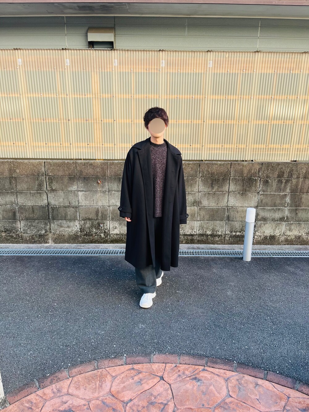 ブラック系のステンカラーコート、ブラウン系のニット/セーター、グレー系のスラックスを着用したメンズの秋コーディネートの2枚目の写真