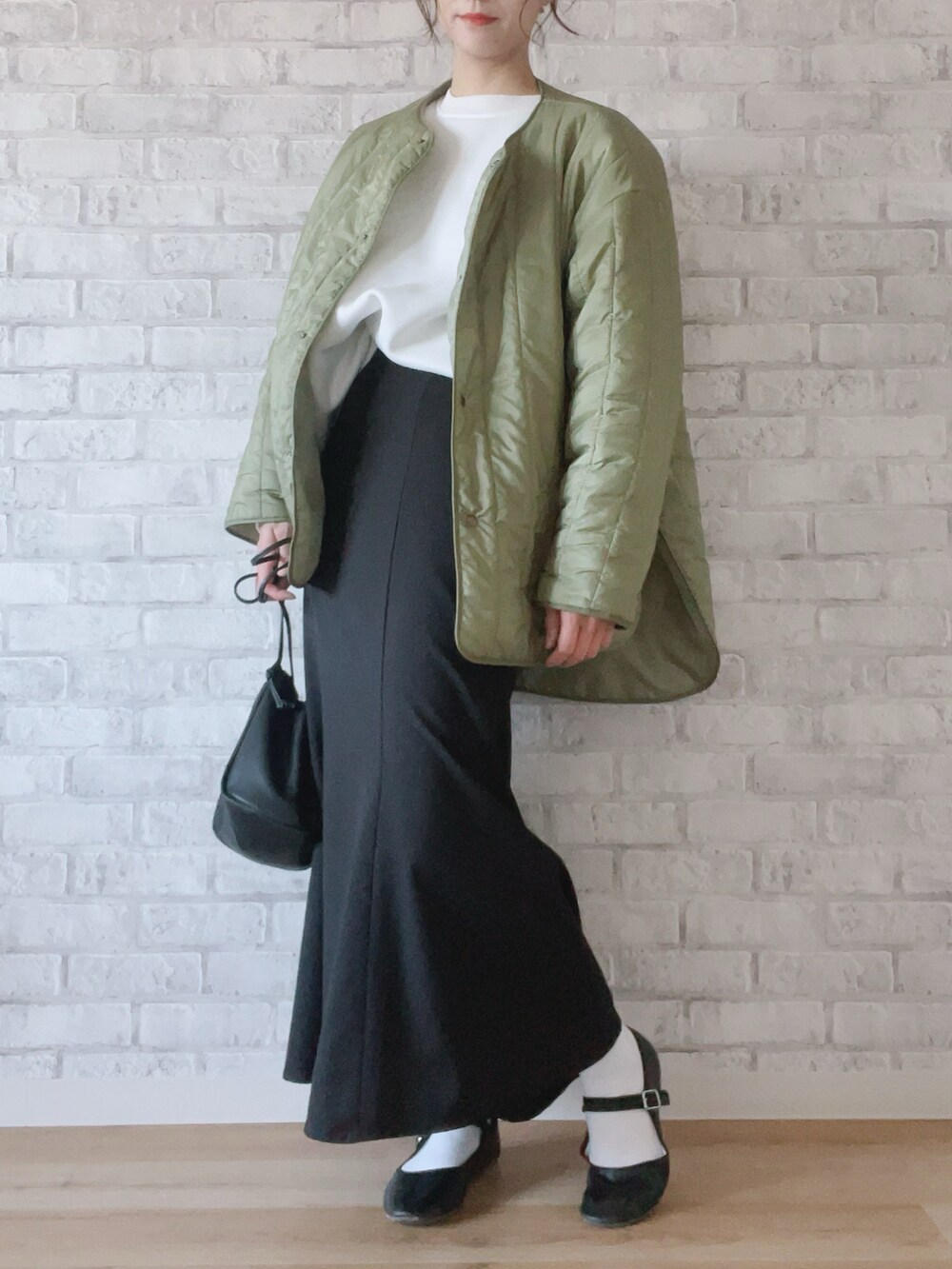 グリーン系のノーカラージャケット、ブラック系のスカート、ブラック系のショルダーバッグを着用したレディースの冬コーディネートの2枚目の写真
