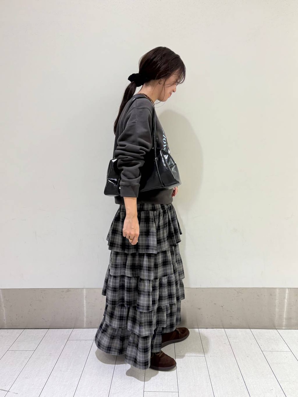 ブラウン系のスニーカー、グレー系のスカート、ブラック系のボストンバッグを着用したレディースの秋コーディネートの3枚目の写真