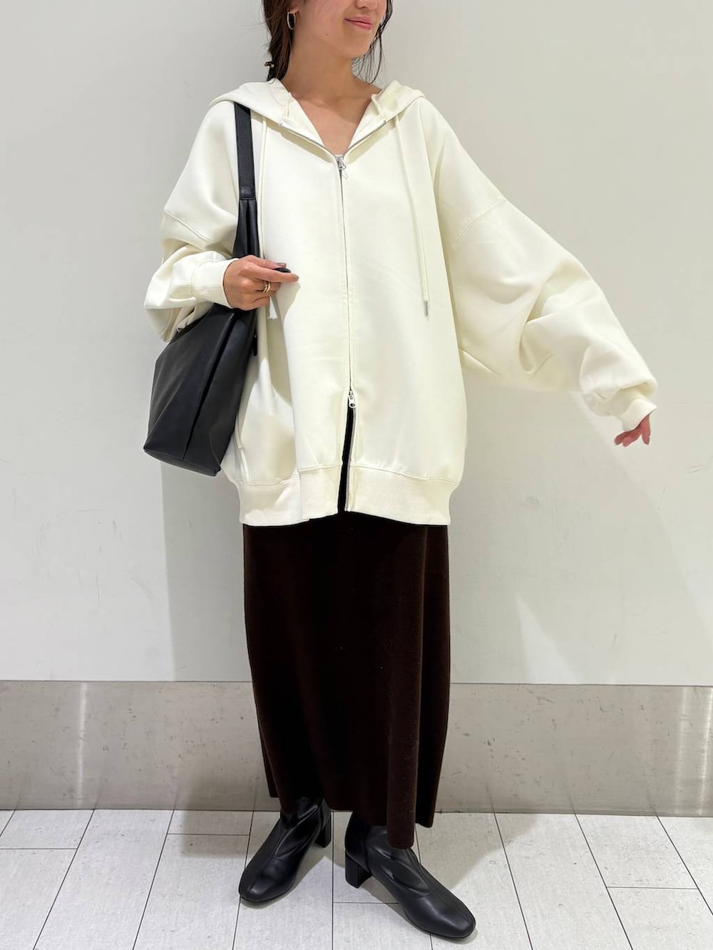 ブラック系のショルダーバッグ、ベージュ系のパーカー、ブラウン系のワンピースを着用したレディースの秋コーディネートの2枚目の写真