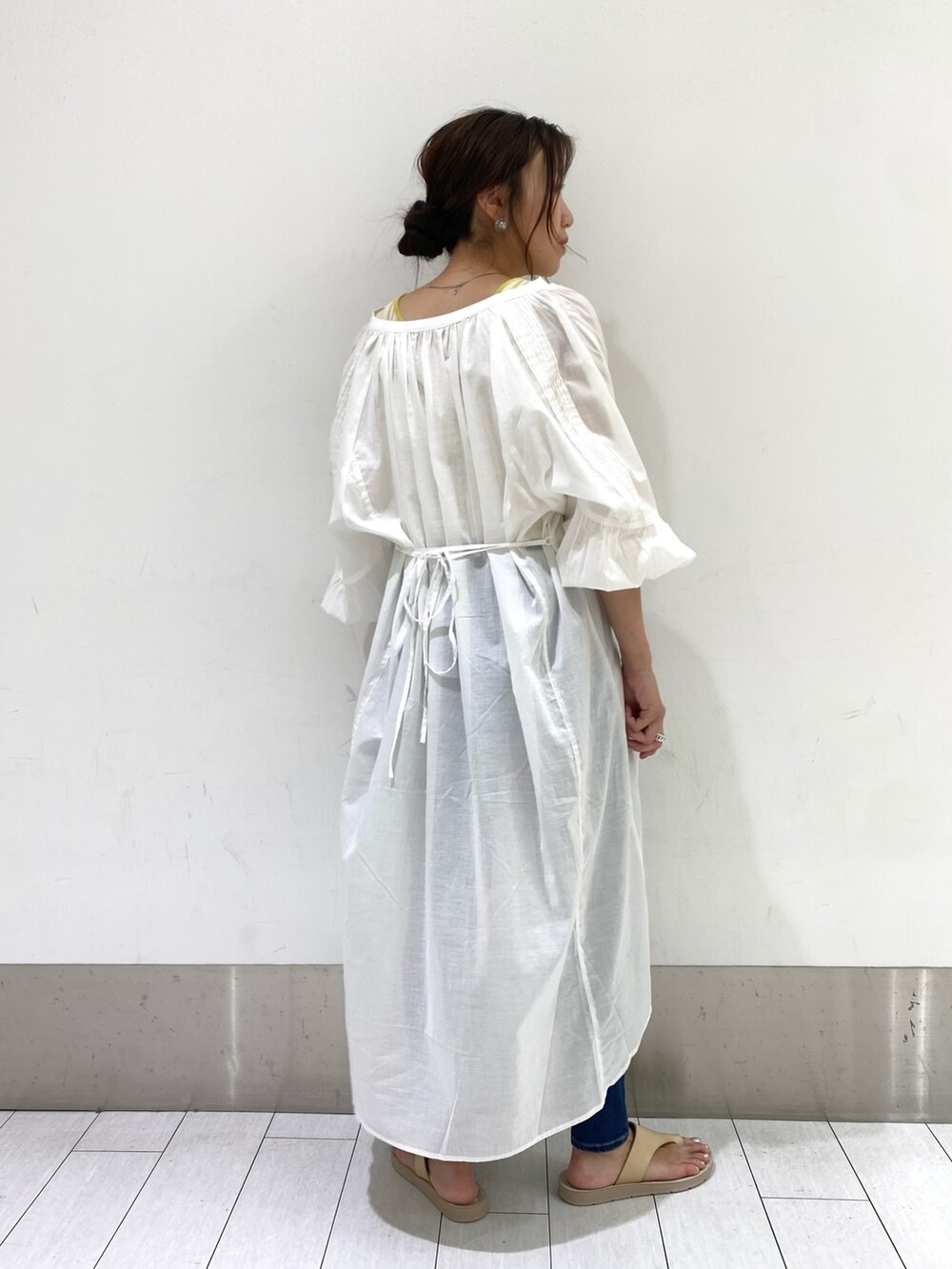 ホワイト系のワンピース、イエロー系のタンクトップ、ブルー系のデニムパンツを着用したレディースの夏コーディネートの2枚目の写真