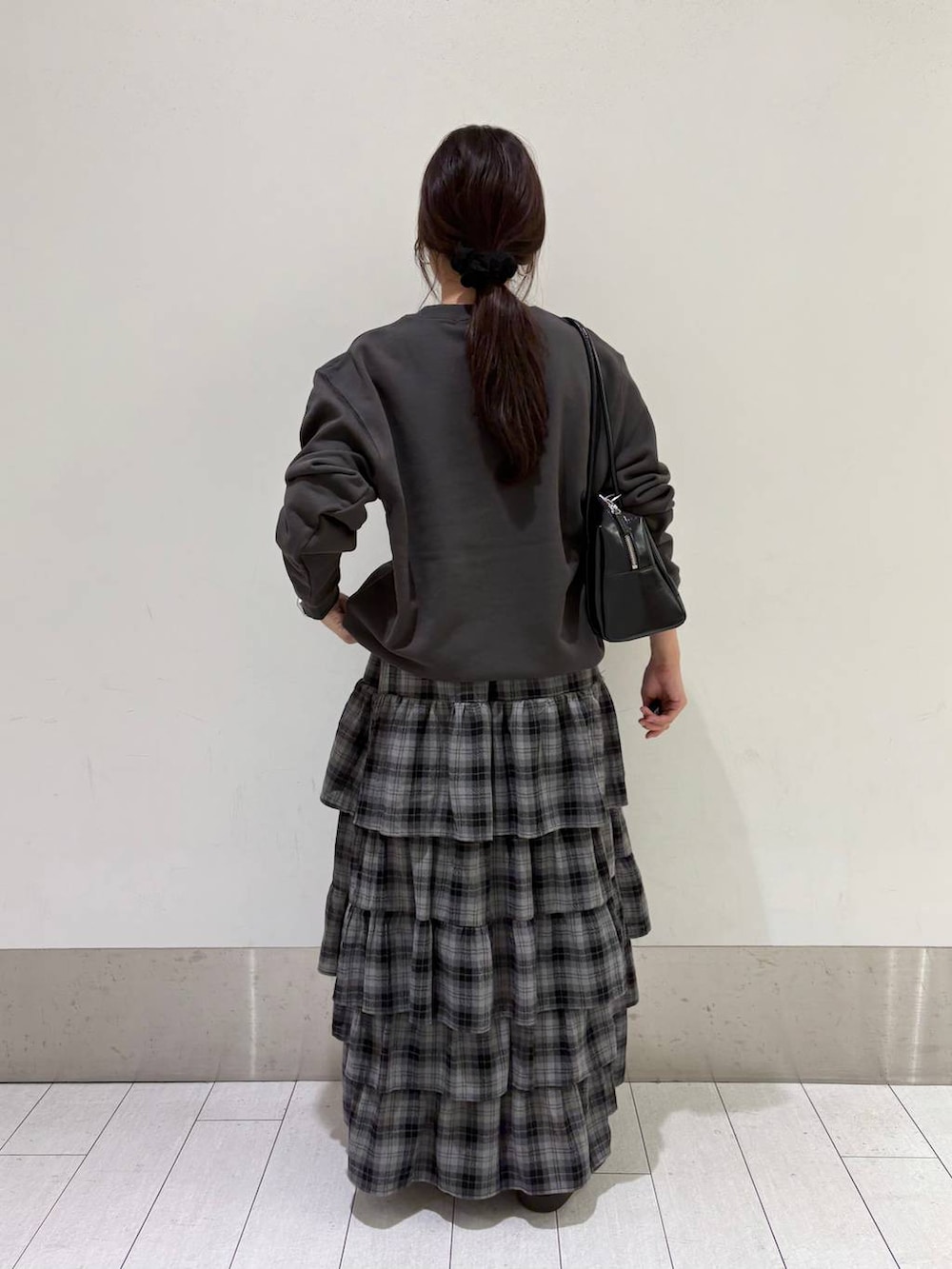 ブラウン系のスニーカー、グレー系のスカート、ブラック系のボストンバッグを着用したレディースの秋コーディネートの4枚目の写真