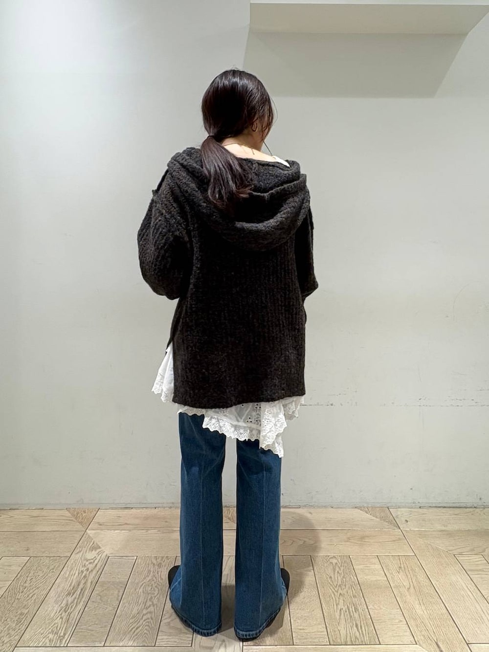 グレー系のニット/セーター、ホワイト系のスカート、ブルー系のデニムパンツを着用したレディースの秋コーディネートの3枚目の写真