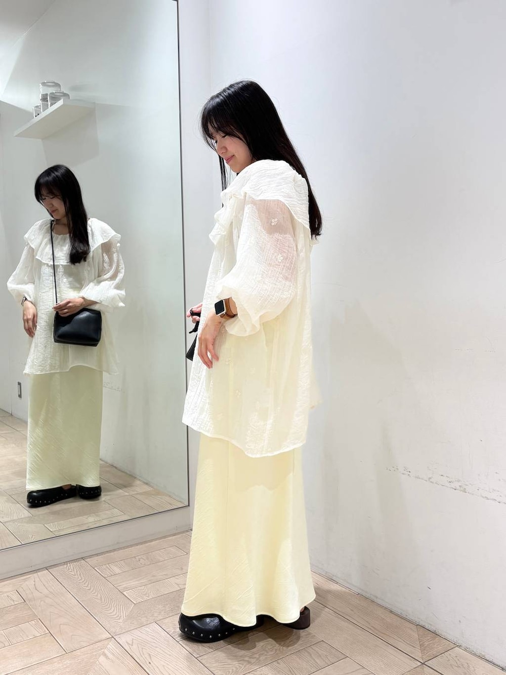 イエロー系のスカート、ゴールド系のタンクトップ、ブラック系のトートバッグを着用したレディースの春コーディネートの2枚目の写真