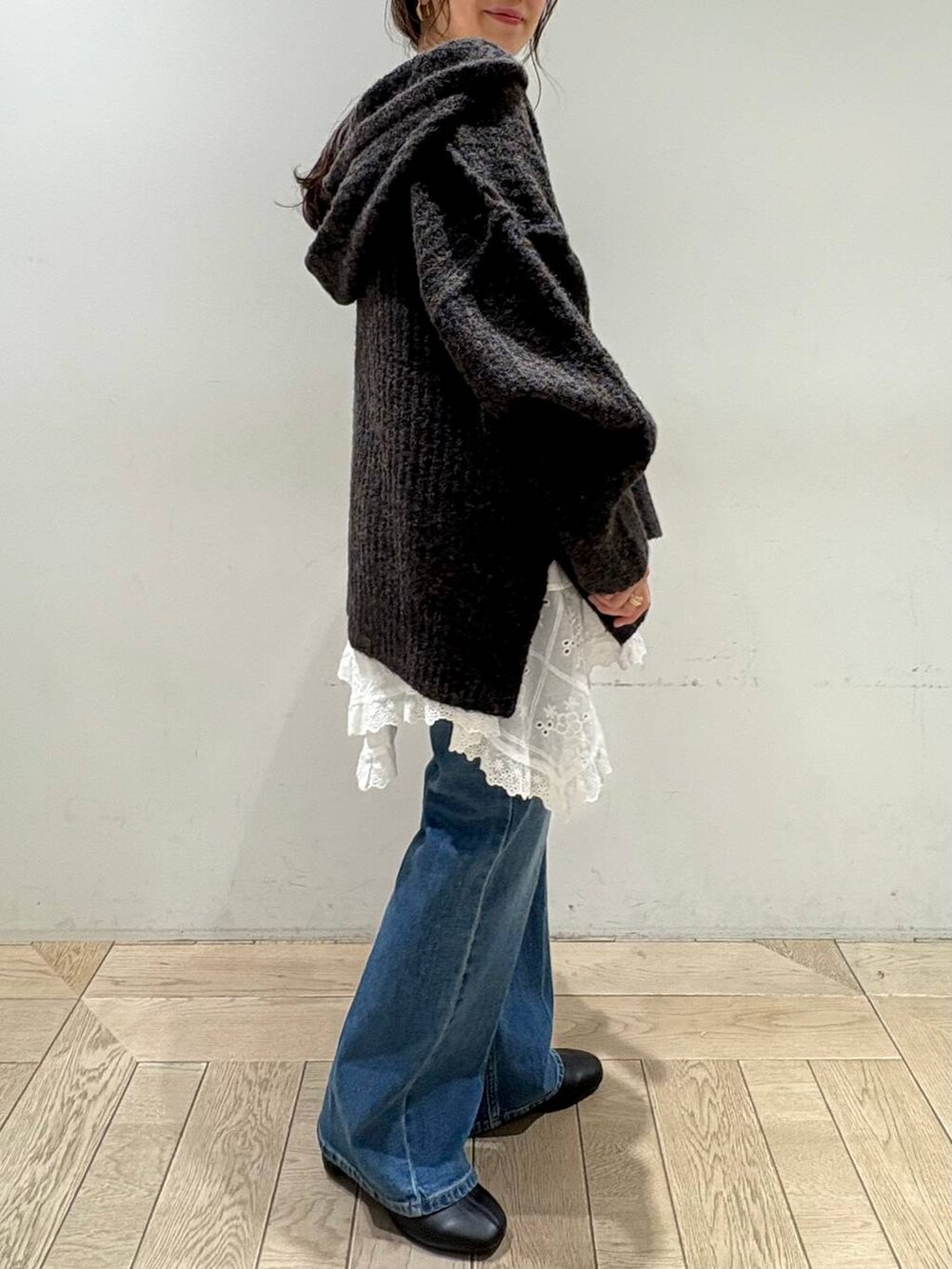 グレー系のニット/セーター、ホワイト系のスカート、ブルー系のデニムパンツを着用したレディースの秋コーディネートの2枚目の写真