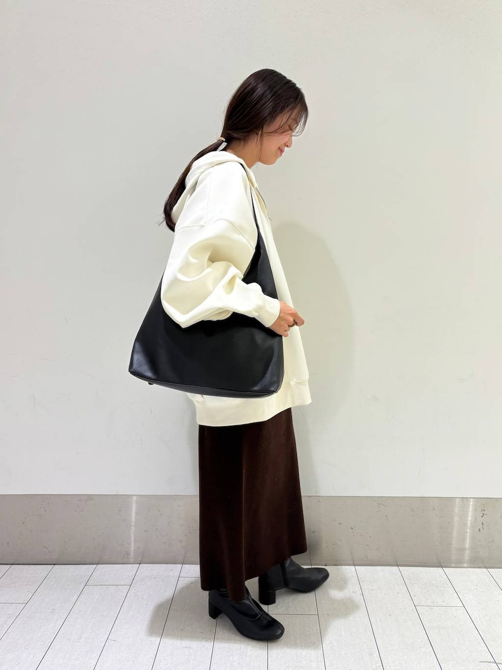 ブラック系のショルダーバッグ、ベージュ系のパーカー、ブラウン系のワンピースを着用したレディースの秋コーディネートの3枚目の写真