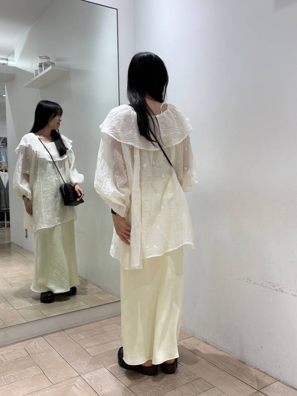 イエロー系のスカート、ゴールド系のタンクトップ、ブラック系のトートバッグを着用したレディースの春コーディネートの3枚目の写真