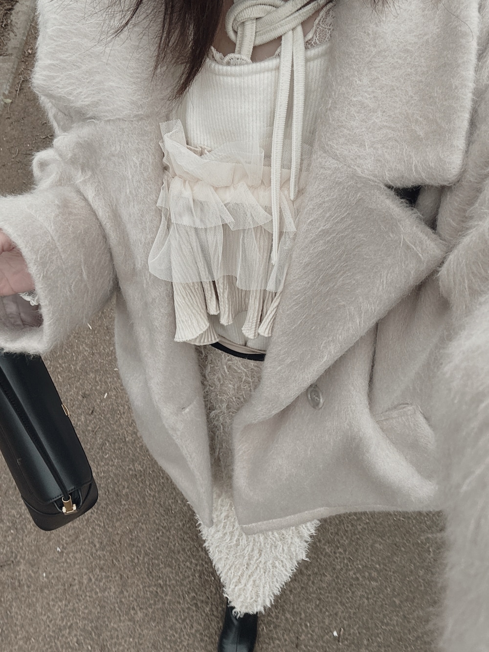 ホワイト系のニット/セーター、ベージュ系のスカート、ブラック系のブーツを着用したレディースの春コーディネートの3枚目の写真