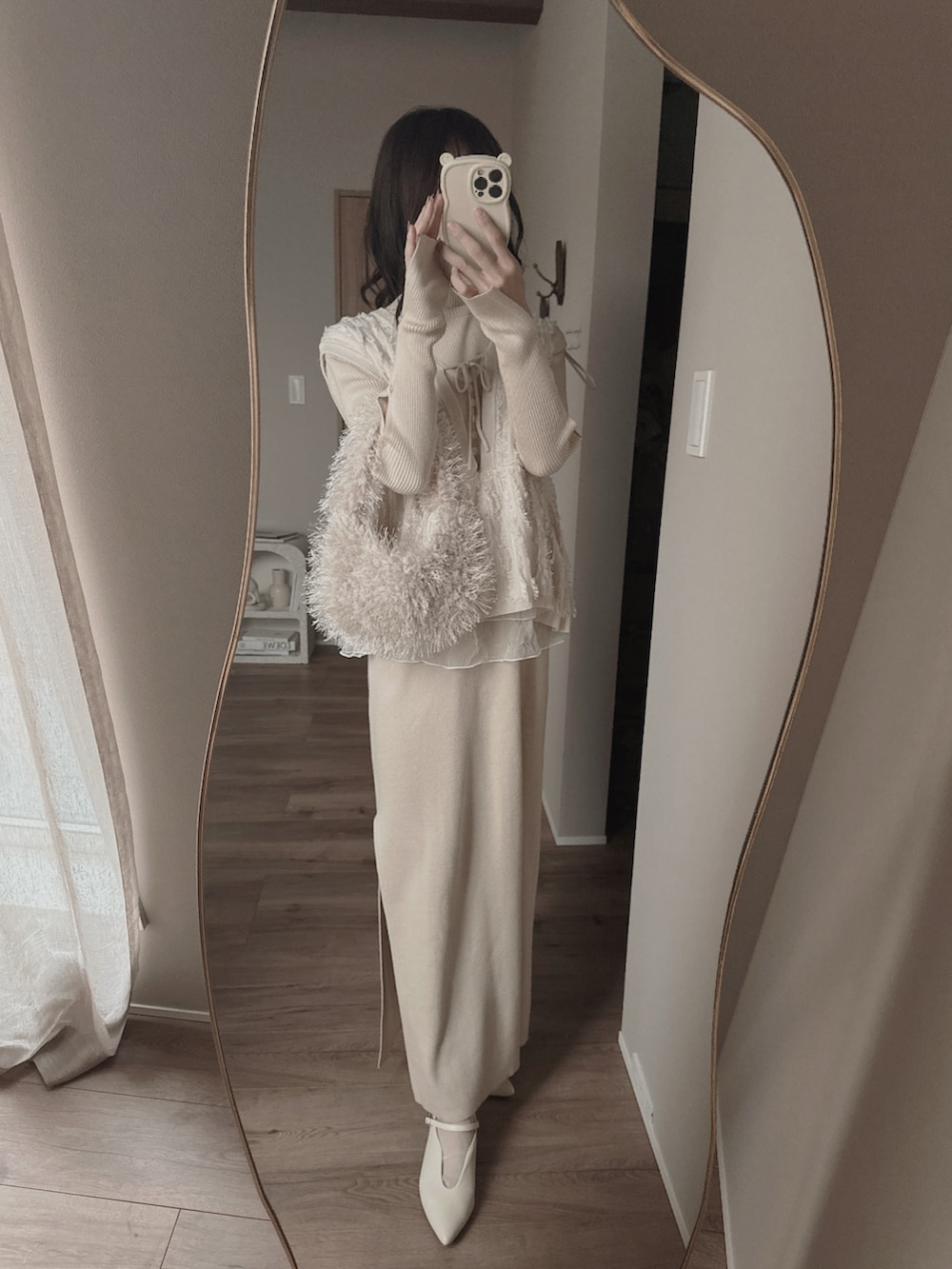 ホワイト系のパンプス、ホワイト系のベスト、ホワイト系のワンピースを着用したレディースの冬コーディネートの2枚目の写真