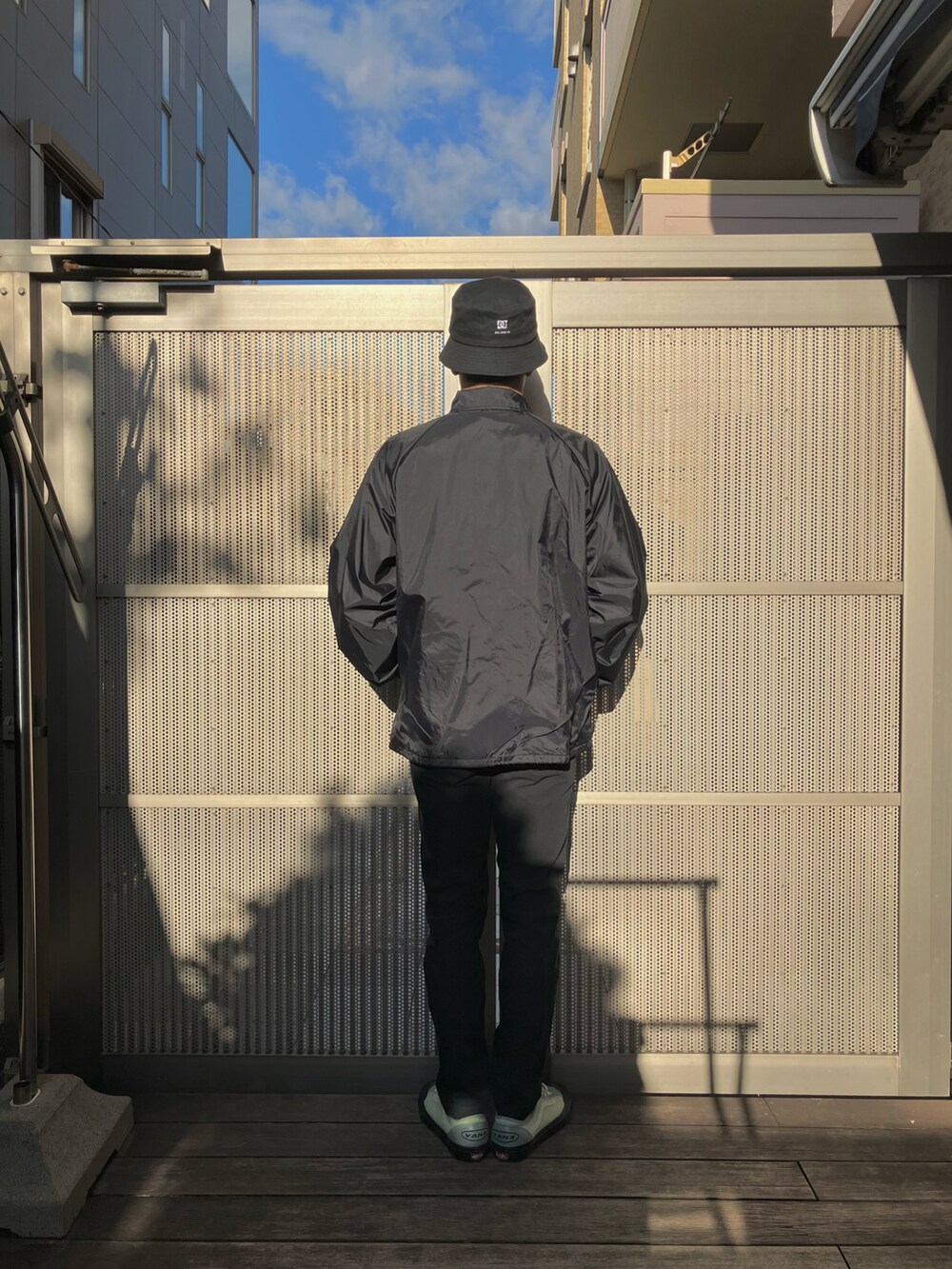 ブラック系のナイロンジャケット、ブラック系のチノパンツ、グリーン系のスニーカーを着用したメンズの冬コーディネートの2枚目の写真