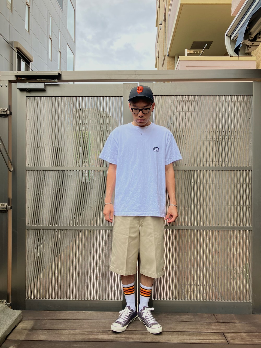 ブラック系のスニーカー、ホワイト系のTシャツ/カットソー、ベージュ系のチノパンツを着用したメンズの夏コーディネートの2枚目の写真