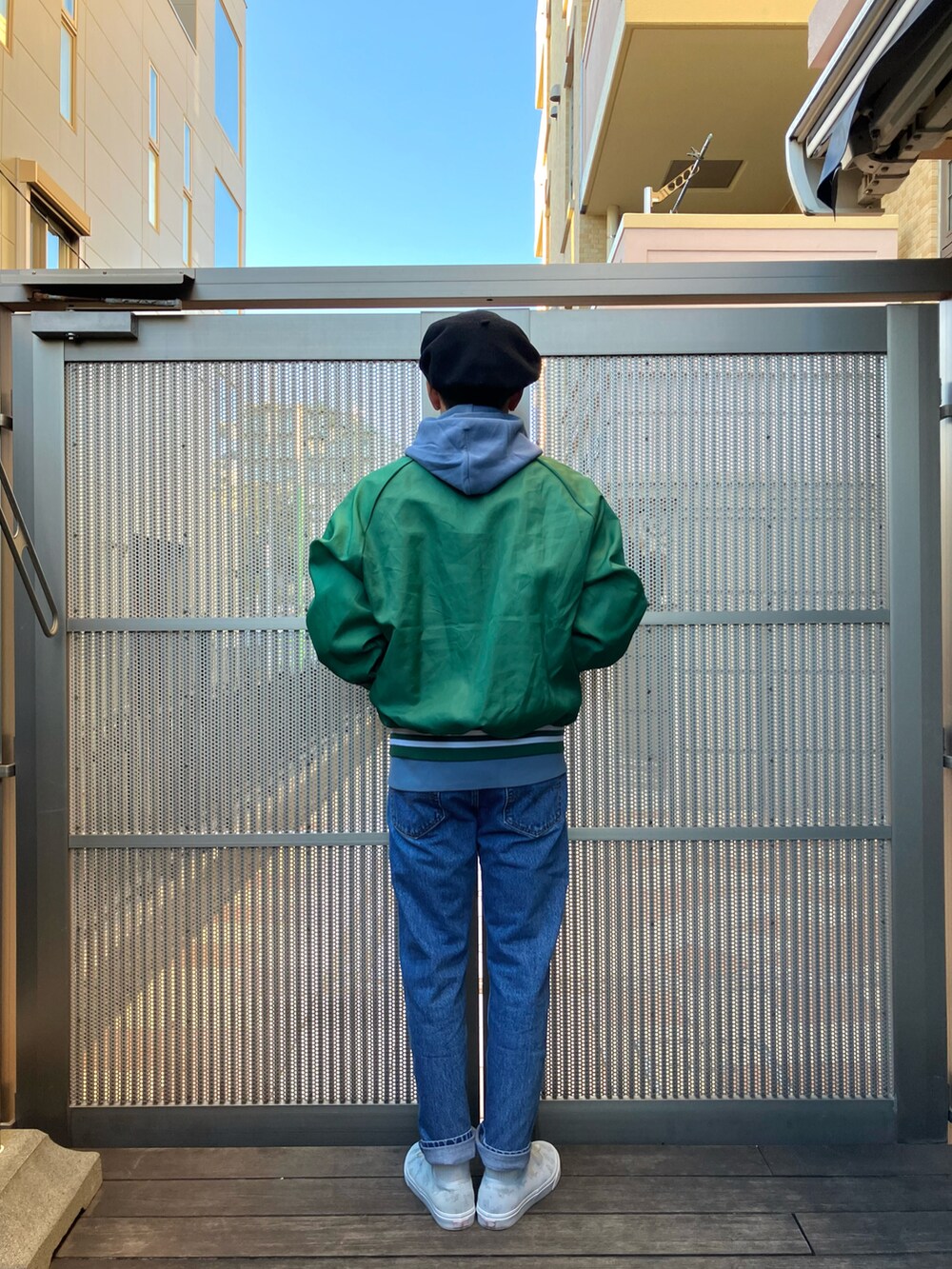 グリーン系のナイロンジャケット、ブルー系のパーカー、ブルー系のデニムパンツを着用したメンズの冬コーディネートの2枚目の写真