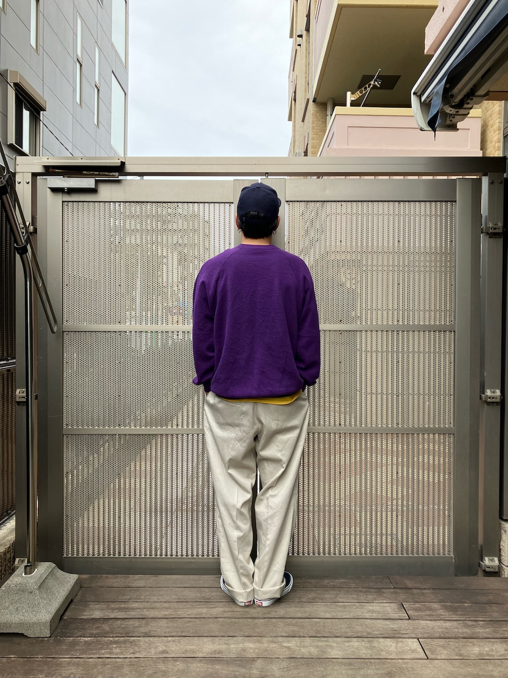 パープル系のスウェット、ベージュ系のチノパンツ、ブルー系のスニーカーを着用したメンズの春コーディネートの2枚目の写真