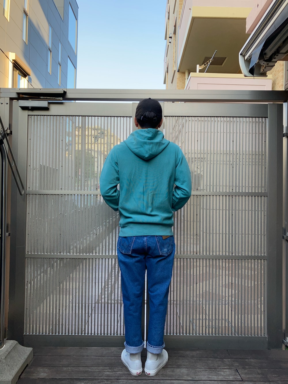 ブルー系のデニムパンツ、グリーン系のパーカー、ホワイト系のスニーカーを着用したメンズの秋コーディネートの2枚目の写真