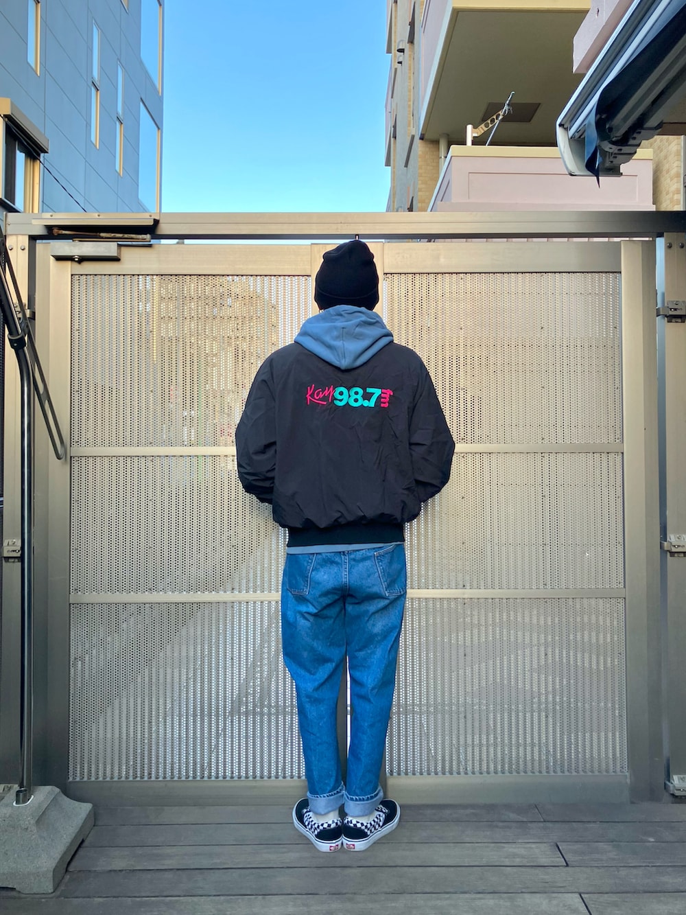 ブラック系のナイロンジャケット、ブルー系のデニムパンツ、ブラック系のスニーカーを着用したメンズの春コーディネートの2枚目の写真