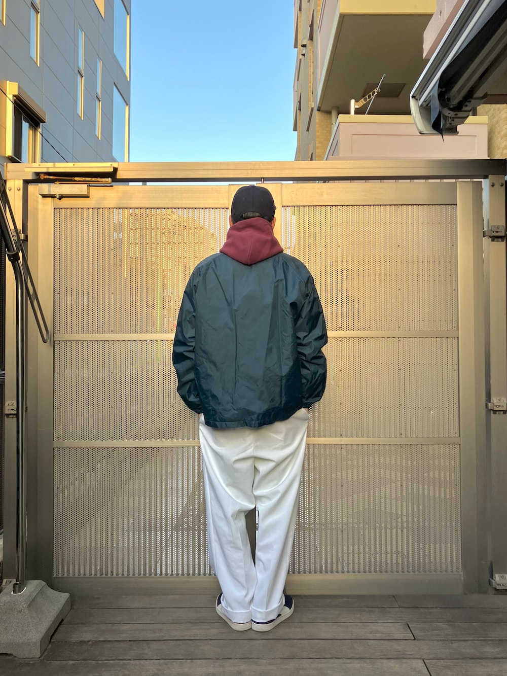 レッド系のパーカー、ブルー系のナイロンジャケット、ホワイト系のパンツを着用したメンズの冬コーディネートの2枚目の写真