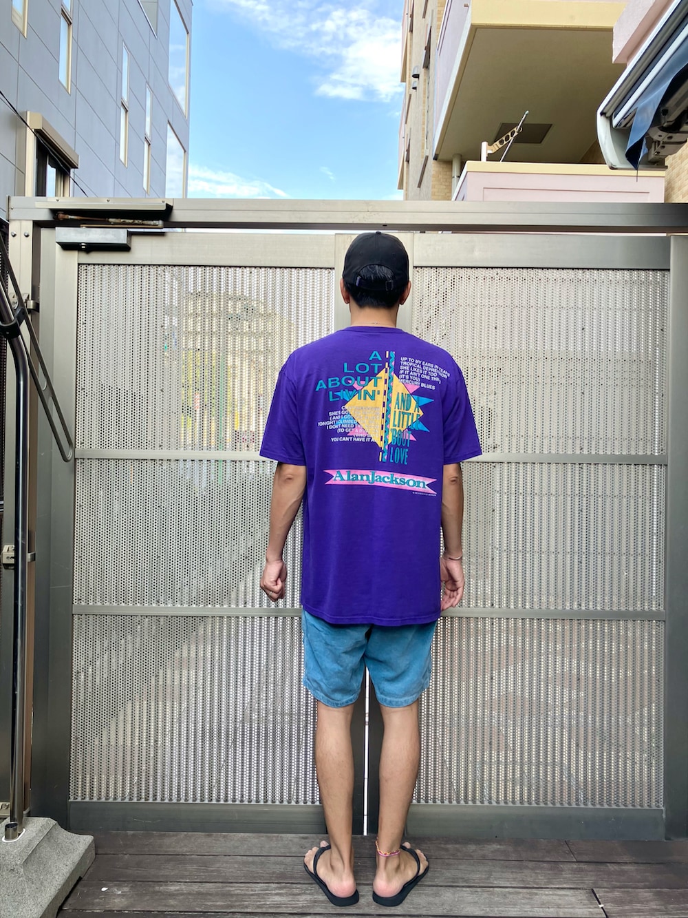 パープル系のTシャツ/カットソー、ブルー系のその他パンツ、ブラック系のビーチサンダルを着用したメンズの秋コーディネートの2枚目の写真