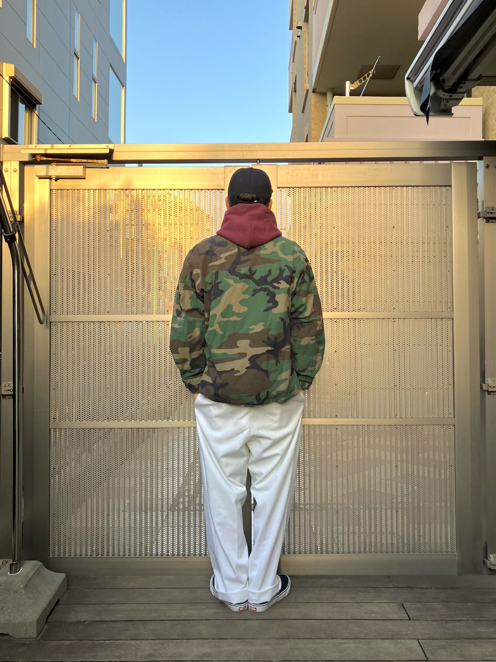 レッド系のパーカー、グリーン系のミリタリージャケット、ホワイト系のパンツを着用したメンズの冬コーディネートの2枚目の写真