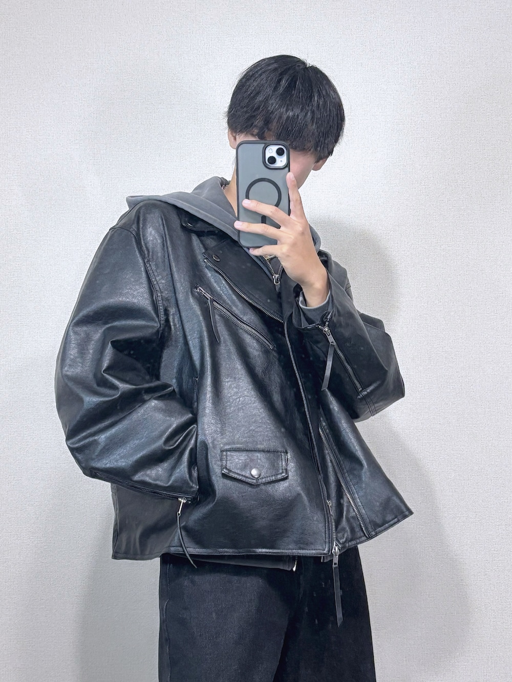 ブラック系のライダースジャケット、グレー系のパーカー、ブラック系のデニムパンツを着用したメンズの冬コーディネートの2枚目の写真