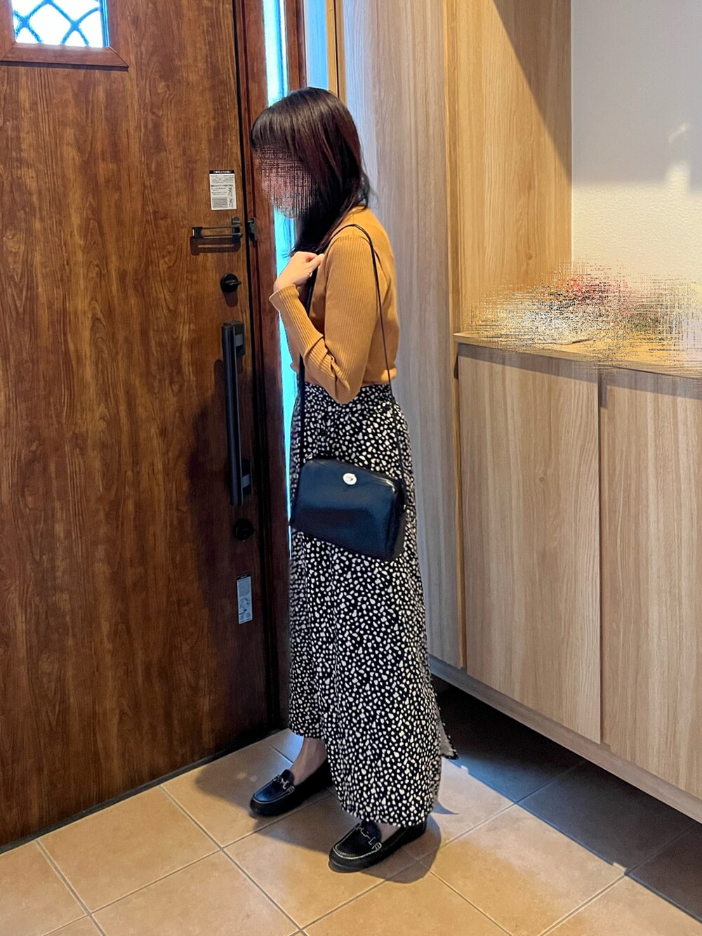 イエロー系のTシャツ/カットソー、ブラック系のスカート、ブラウン系のローファーを着用したレディースの秋コーディネートの3枚目の写真