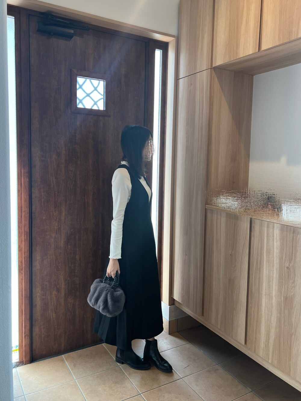 ブラック系のジャンパースカート、ホワイト系のTシャツ/カットソー、グレー系のハンドバッグを着用したレディースの秋コーディネートの2枚目の写真