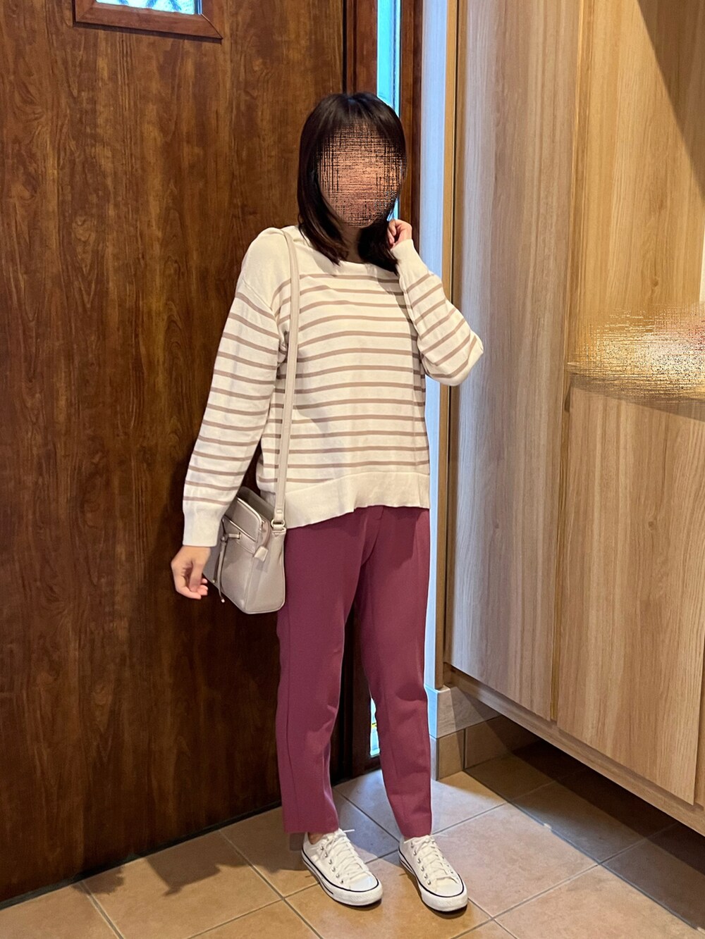 ピンク系のパンツ、ベージュ系のニット/セーター、ホワイト系のスニーカーを着用したレディースの秋コーディネートの2枚目の写真