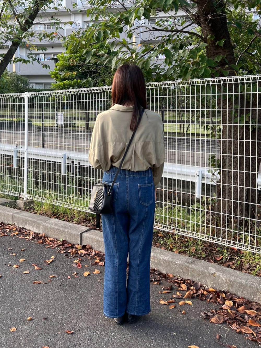 グリーン系のシャツ/ブラウス、ブラック系のショルダーバッグ、ブルー系のデニムパンツを着用したレディースの秋コーディネートの4枚目の写真