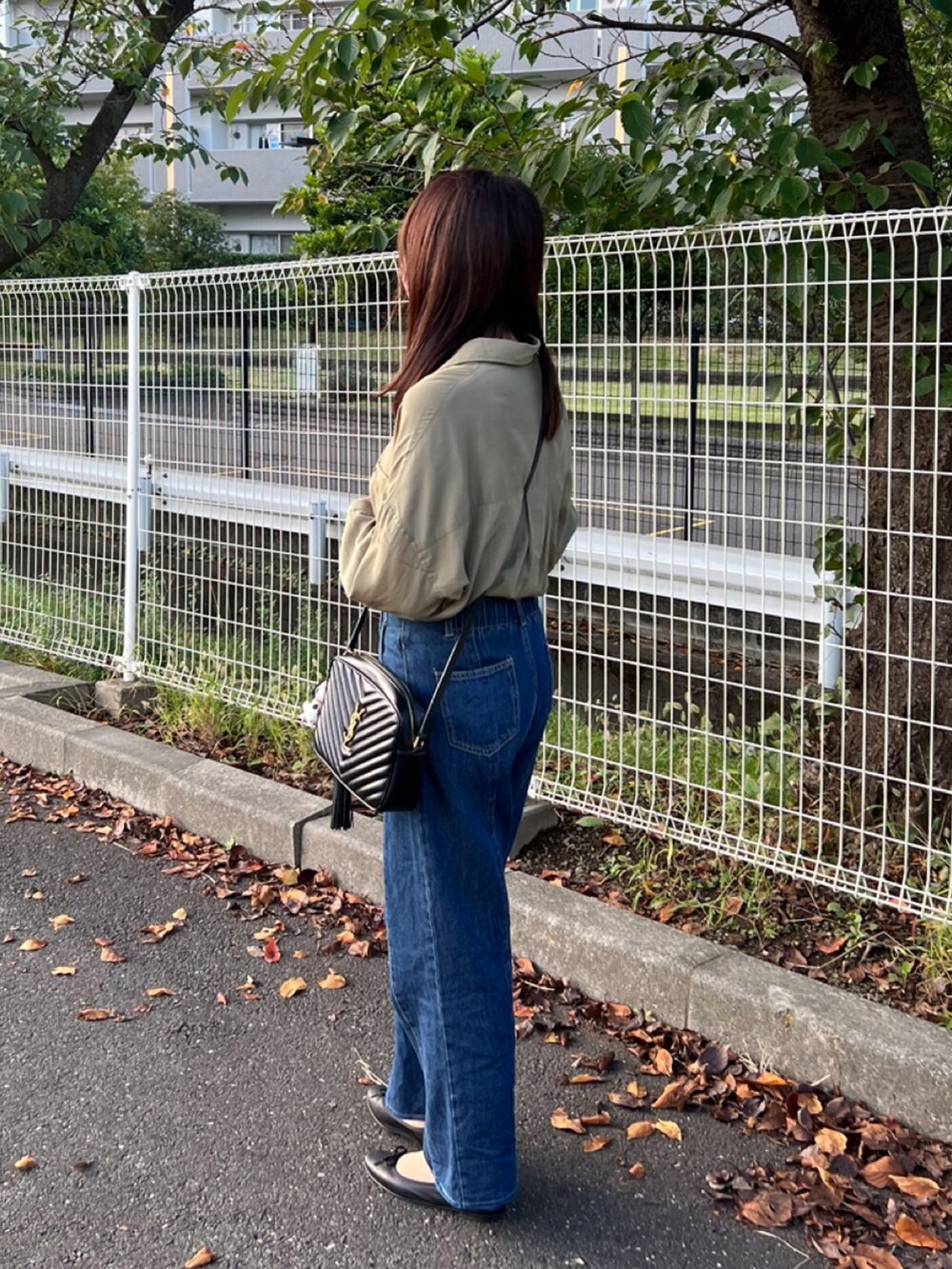 グリーン系のシャツ/ブラウス、ブラック系のショルダーバッグ、ブルー系のデニムパンツを着用したレディースの秋コーディネートの3枚目の写真