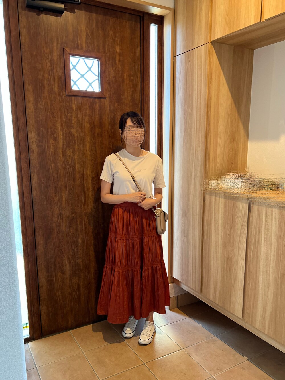 オレンジ系のスカート、ホワイト系のスニーカー、ベージュ系のTシャツ/カットソーを着用したレディースの秋コーディネートの4枚目の写真