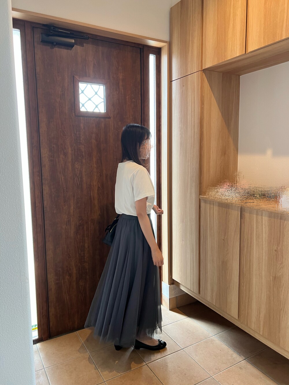 グレー系のスカート、ホワイト系のTシャツ/カットソー、ブラック系のパンプスを着用したレディースの秋コーディネートの2枚目の写真