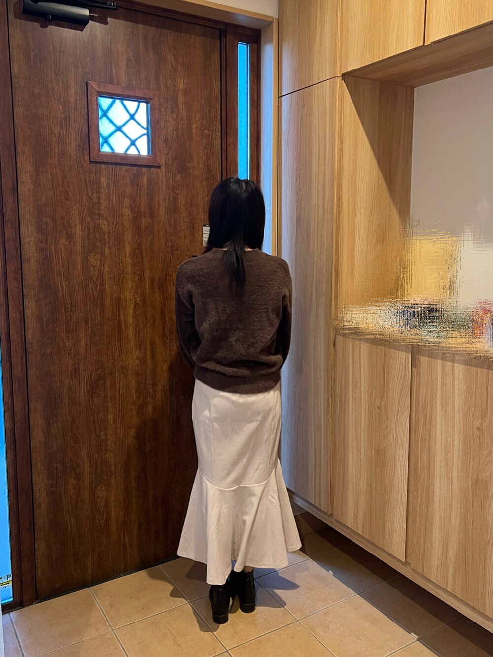 ホワイト系のスカート、ブラック系のブーツ、ブラウン系のTシャツ/カットソーを着用したレディースの冬コーディネートの3枚目の写真