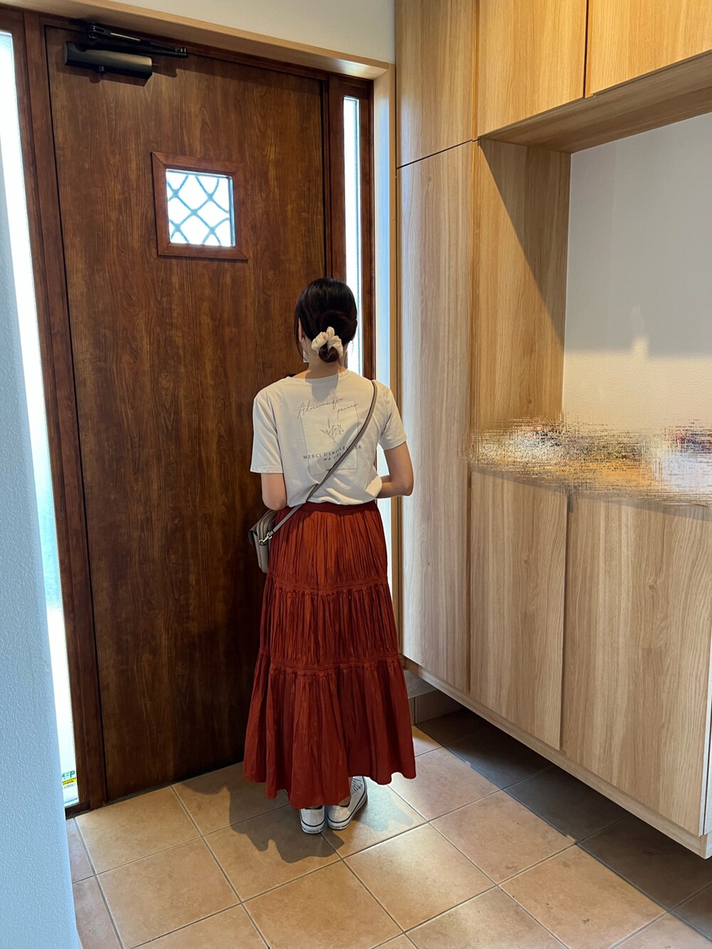 オレンジ系のスカート、ホワイト系のスニーカー、ベージュ系のTシャツ/カットソーを着用したレディースの秋コーディネートの2枚目の写真