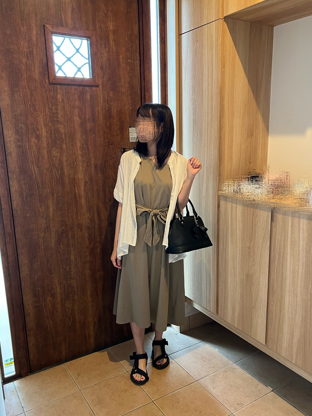 グリーン系のワンピース、ブラック系のサンダル、ブラック系のハンドバッグを着用したレディースの夏コーディネートの3枚目の写真