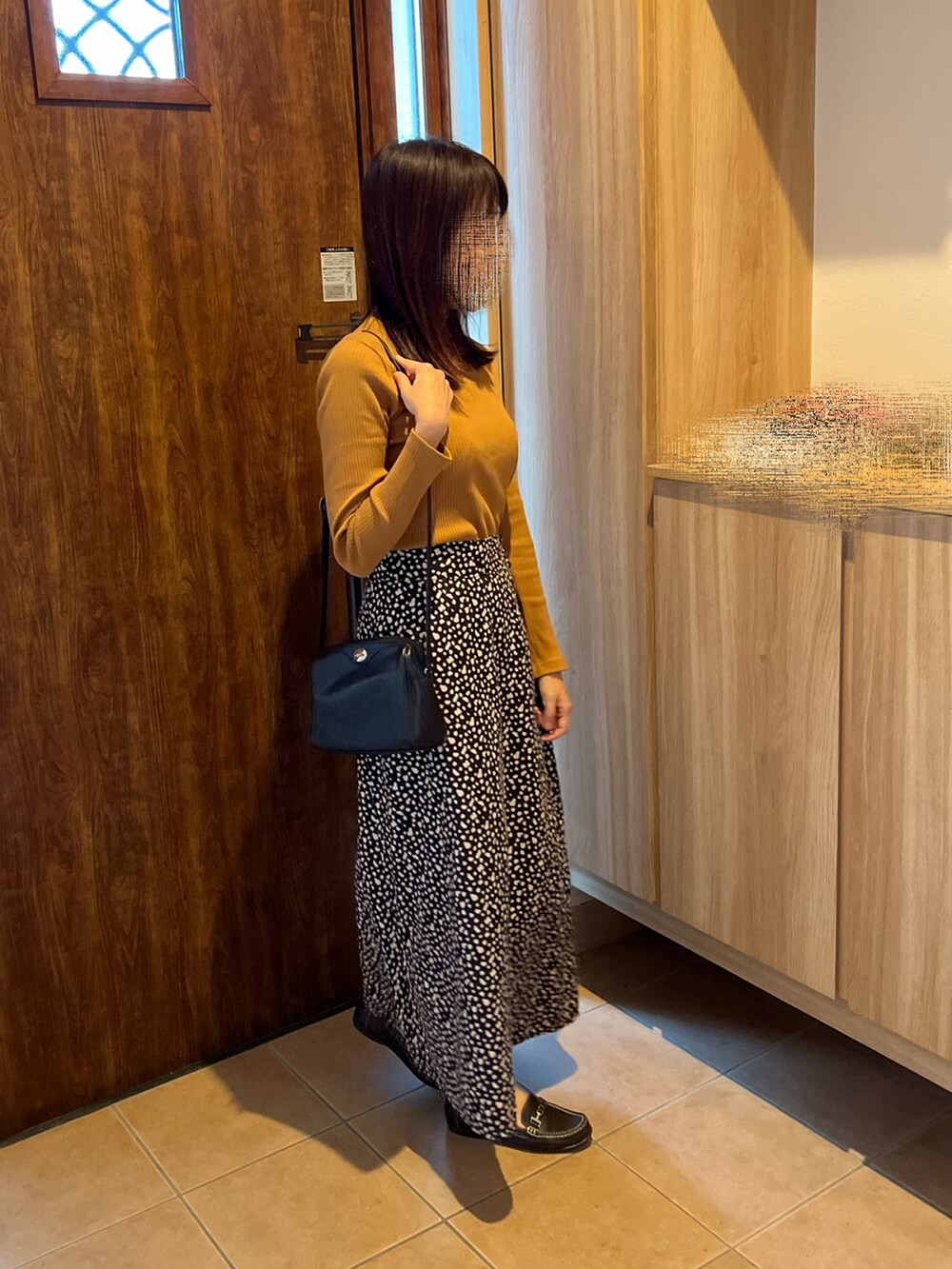 イエロー系のTシャツ/カットソー、ブラック系のスカート、ブラウン系のローファーを着用したレディースの秋コーディネートの2枚目の写真