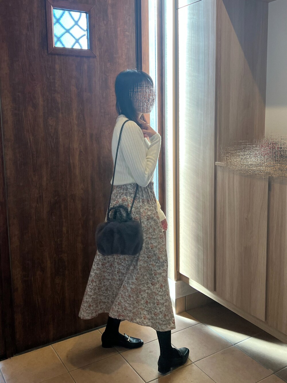 ホワイト系のニット/セーター、ホワイト系のスカート、グレー系のハンドバッグを着用したレディースの冬コーディネートの2枚目の写真