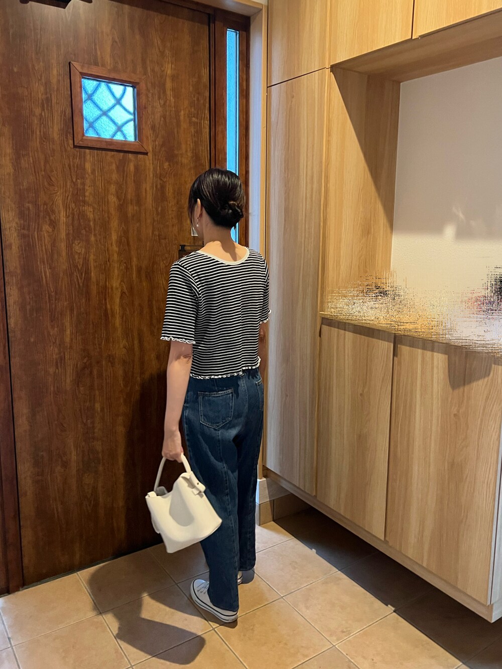 ブラック系のTシャツ/カットソー、ブルー系のデニムパンツ、ホワイト系のスニーカーを着用したレディースの春コーディネートの3枚目の写真