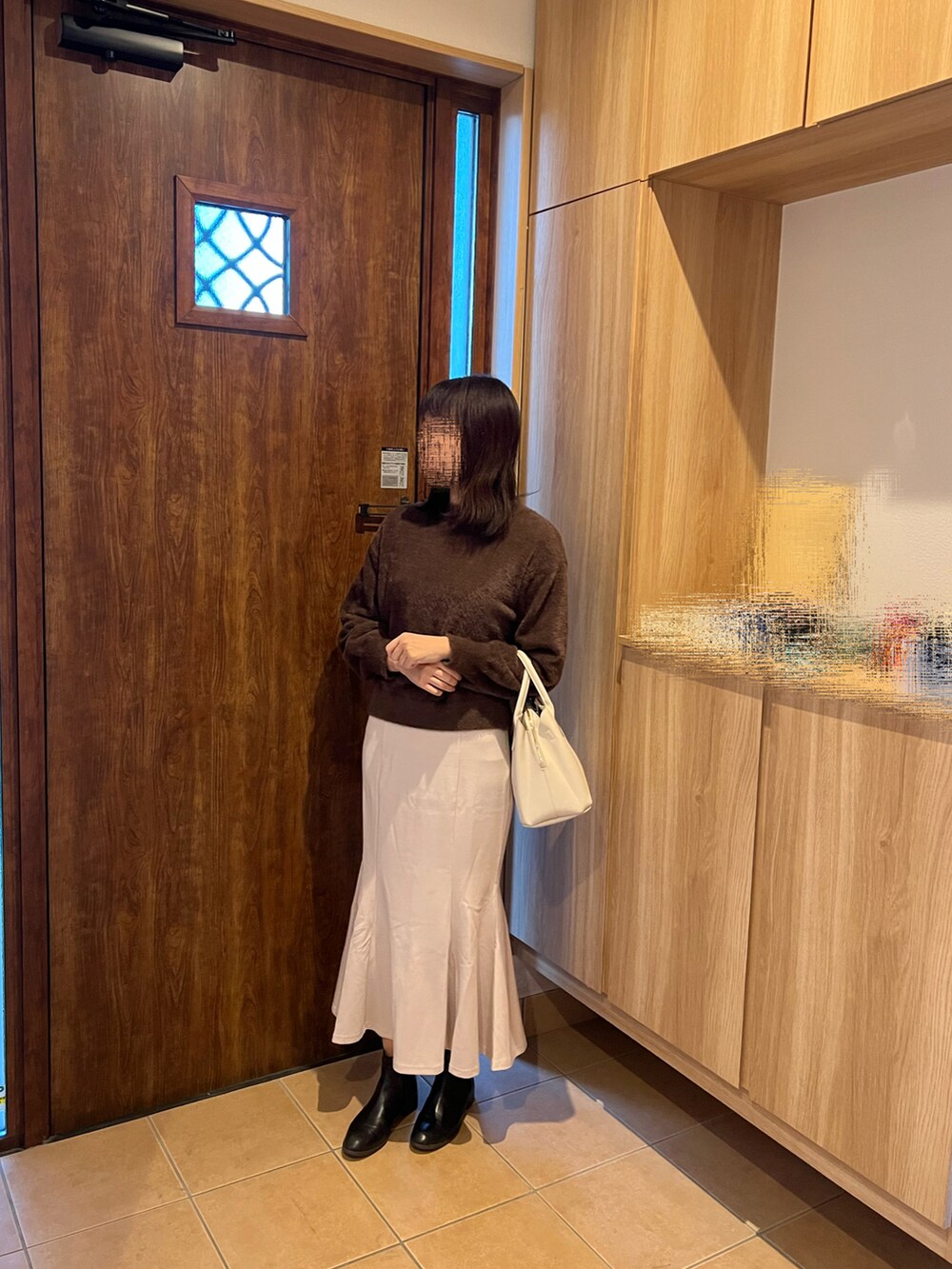 ホワイト系のスカート、ブラック系のブーツ、ブラウン系のTシャツ/カットソーを着用したレディースの冬コーディネートの2枚目の写真