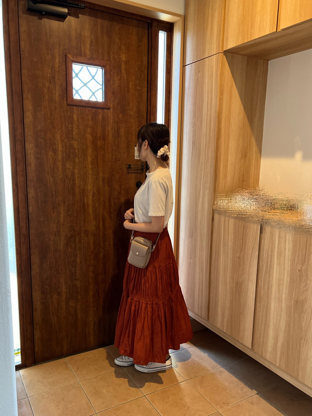 オレンジ系のスカート、ホワイト系のスニーカー、ベージュ系のTシャツ/カットソーを着用したレディースの秋コーディネートの3枚目の写真