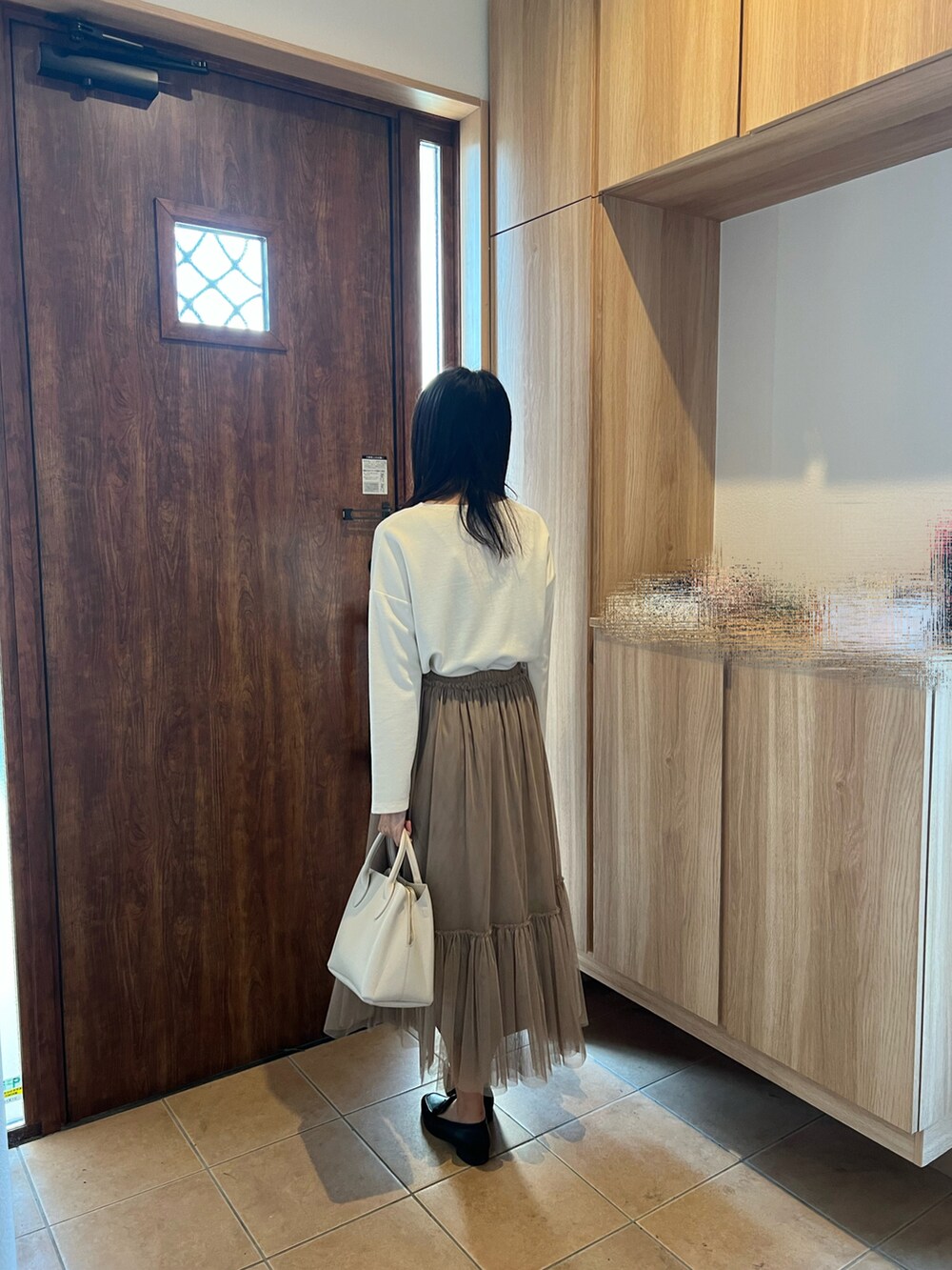 ベージュ系のスカート、ホワイト系のTシャツ/カットソー、ホワイト系のハンドバッグを着用したレディースの秋コーディネートの2枚目の写真