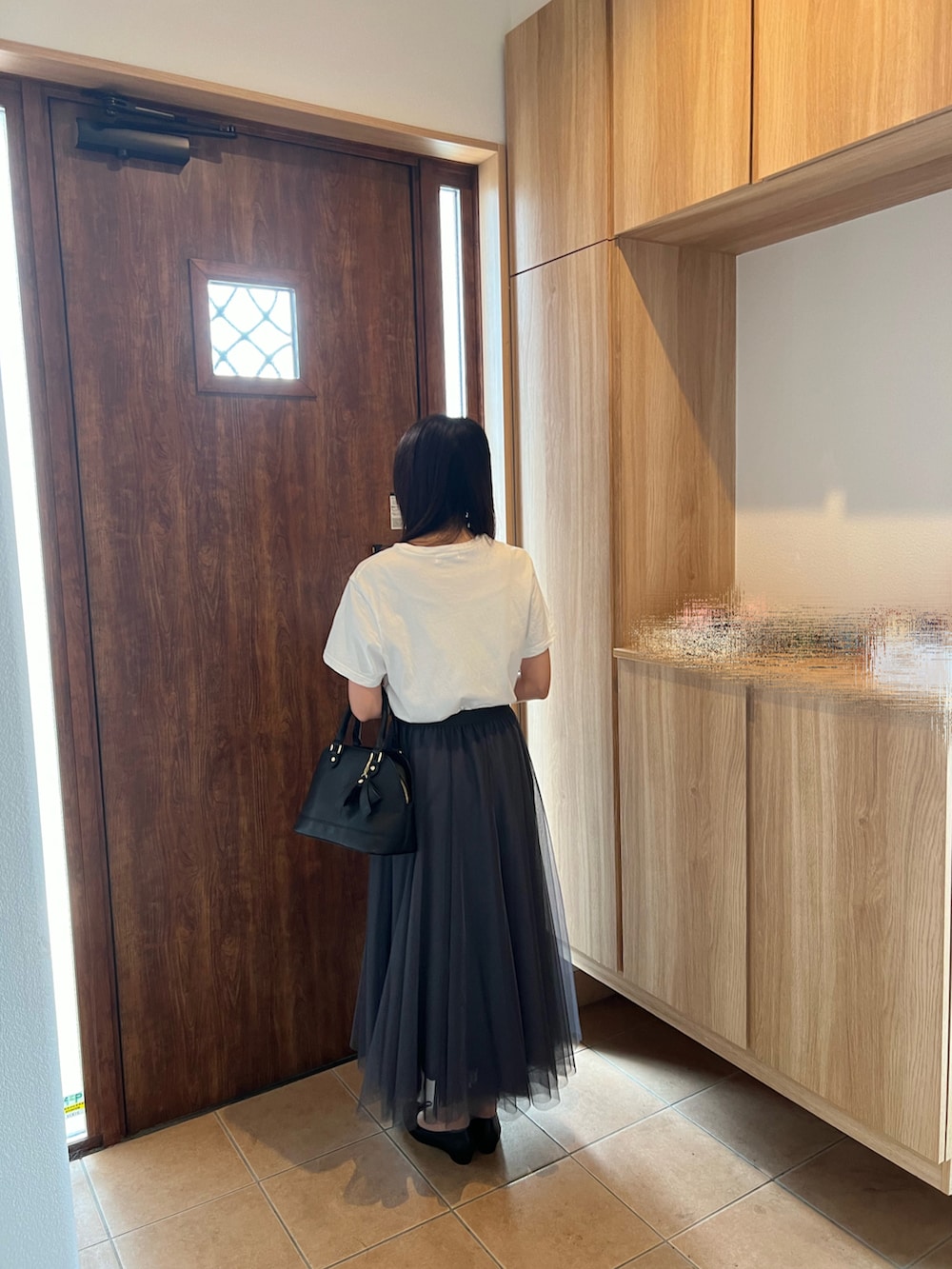 グレー系のスカート、ホワイト系のTシャツ/カットソー、ブラック系のパンプスを着用したレディースの秋コーディネートの3枚目の写真