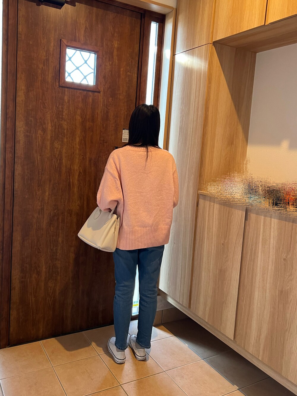 ピンク系のニット/セーター、ブルー系のデニムパンツ、ホワイト系のハンドバッグを着用したレディースの冬コーディネートの2枚目の写真