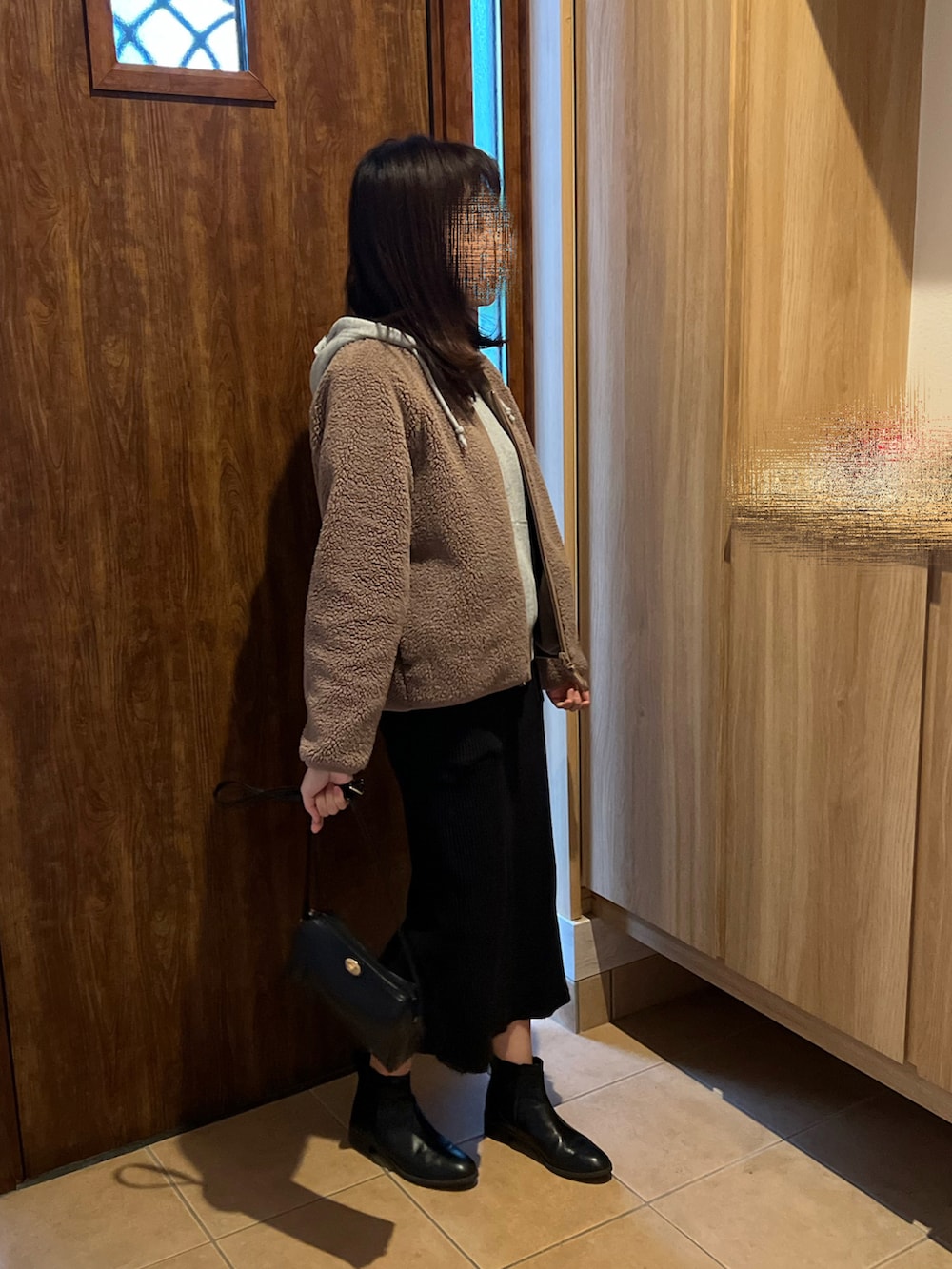 ブラック系のスカート、ブラック系のブーツ、ブラウン系のブルゾンを着用したレディースの冬コーディネートの2枚目の写真