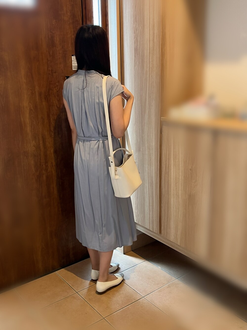 ホワイト系のショルダーバッグ、ホワイト系のパンプス、ブルー系のワンピースを着用したレディースの秋コーディネートの3枚目の写真