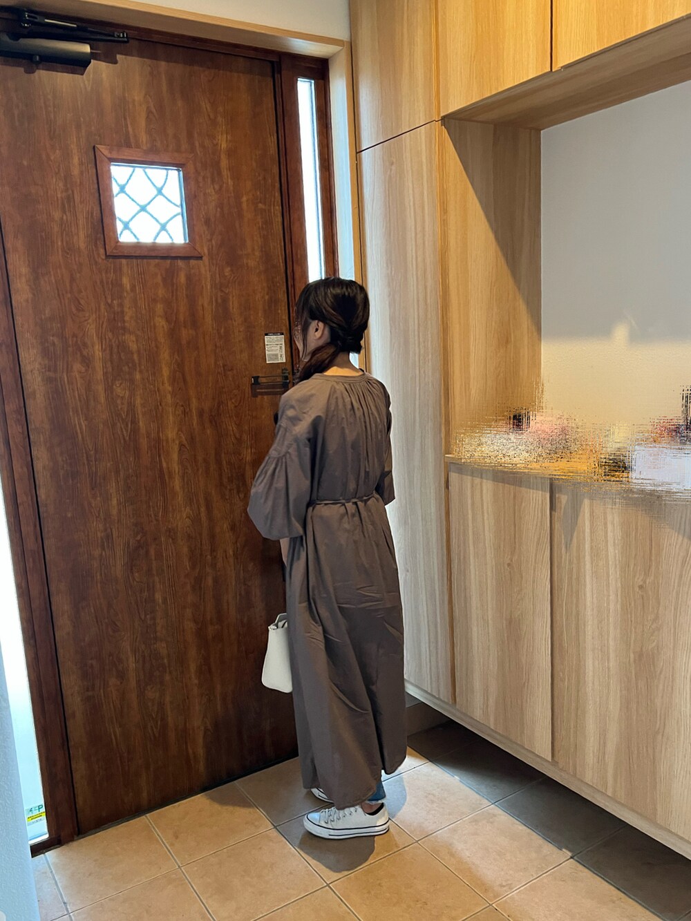 ブラウン系のワンピース、ブルー系のデニムパンツ、ホワイト系のスニーカーを着用したレディースの夏コーディネートの2枚目の写真