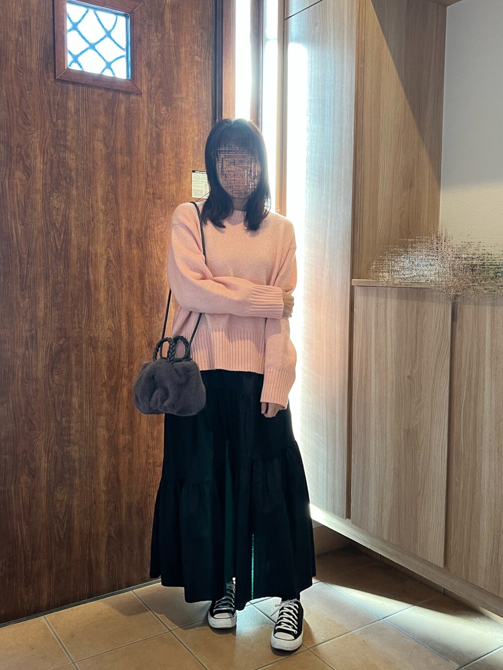 ピンク系のニット/セーター、ブラック系のスカート、ブラック系のスニーカーを着用したレディースの冬コーディネートの2枚目の写真