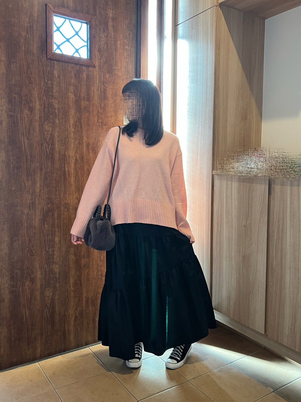 ピンク系のニット/セーター、ブラック系のスカート、ブラック系のスニーカーを着用したレディースの冬コーディネートの3枚目の写真