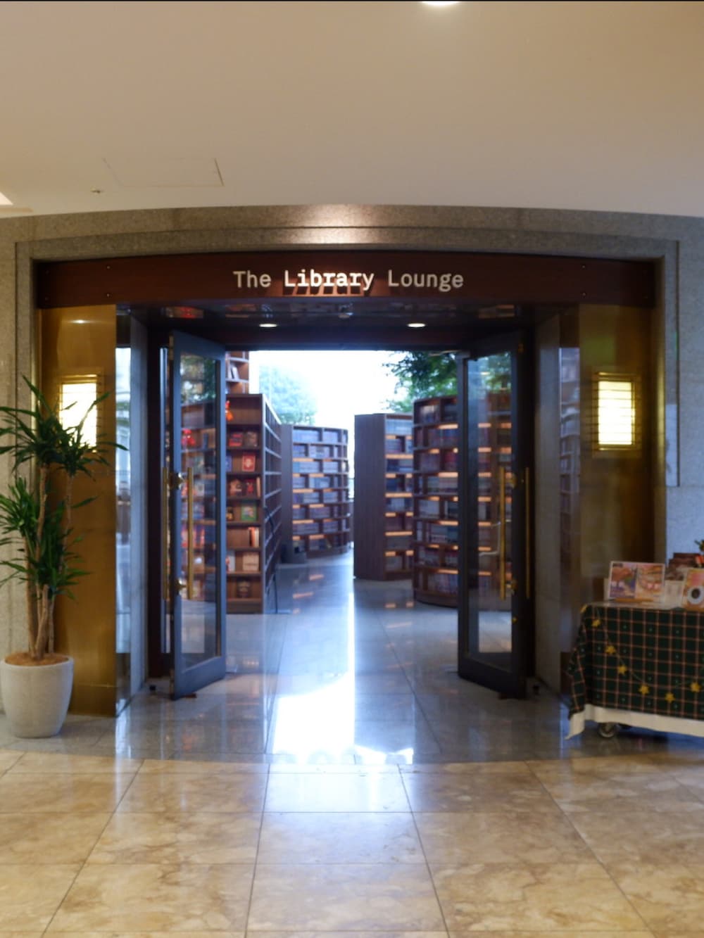 ブラウン系のレインシューズ、ブラウン系のチェスターコート、ベージュ系のショルダーバッグを着用したメンズの秋コーディネートの2枚目の写真