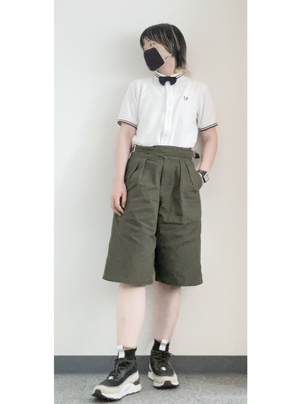 グリーン系のチノパンツ、ブラック系のスニーカー、ホワイト系のポロシャツを着用したメンズの夏コーディネートの2枚目の写真