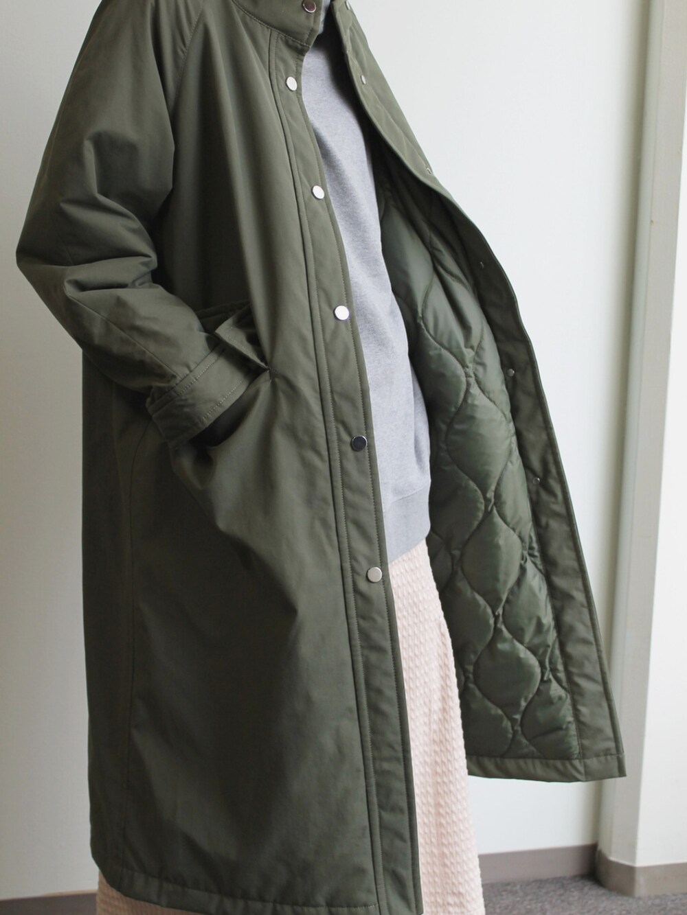 グリーン系のジャケット/アウター、ホワイト系のスカート、グレー系のパーカーを着用したレディースの秋コーディネートの2枚目の写真