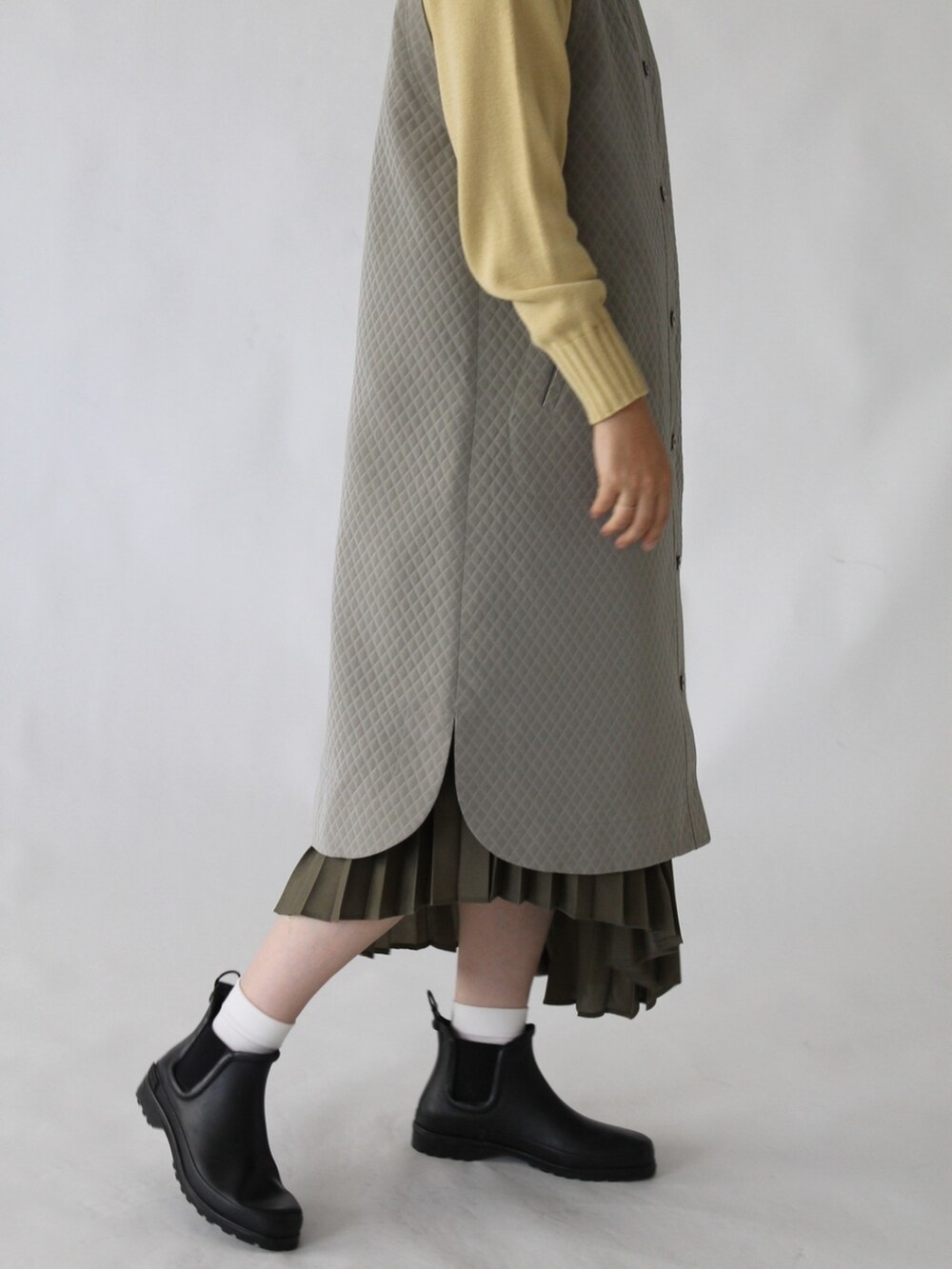 グリーン系のスカート、グリーン系のワンピース、イエロー系のニット/セーターを着用したレディースの冬コーディネートの2枚目の写真